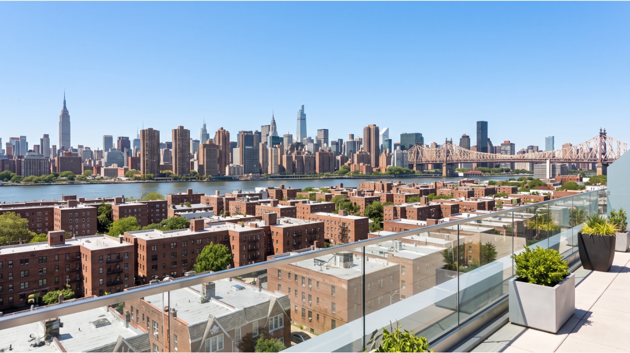 Rooftop terrace in Astoria, Queens looking across low-rise brick buildings toward the Manhattan skyline across the East River